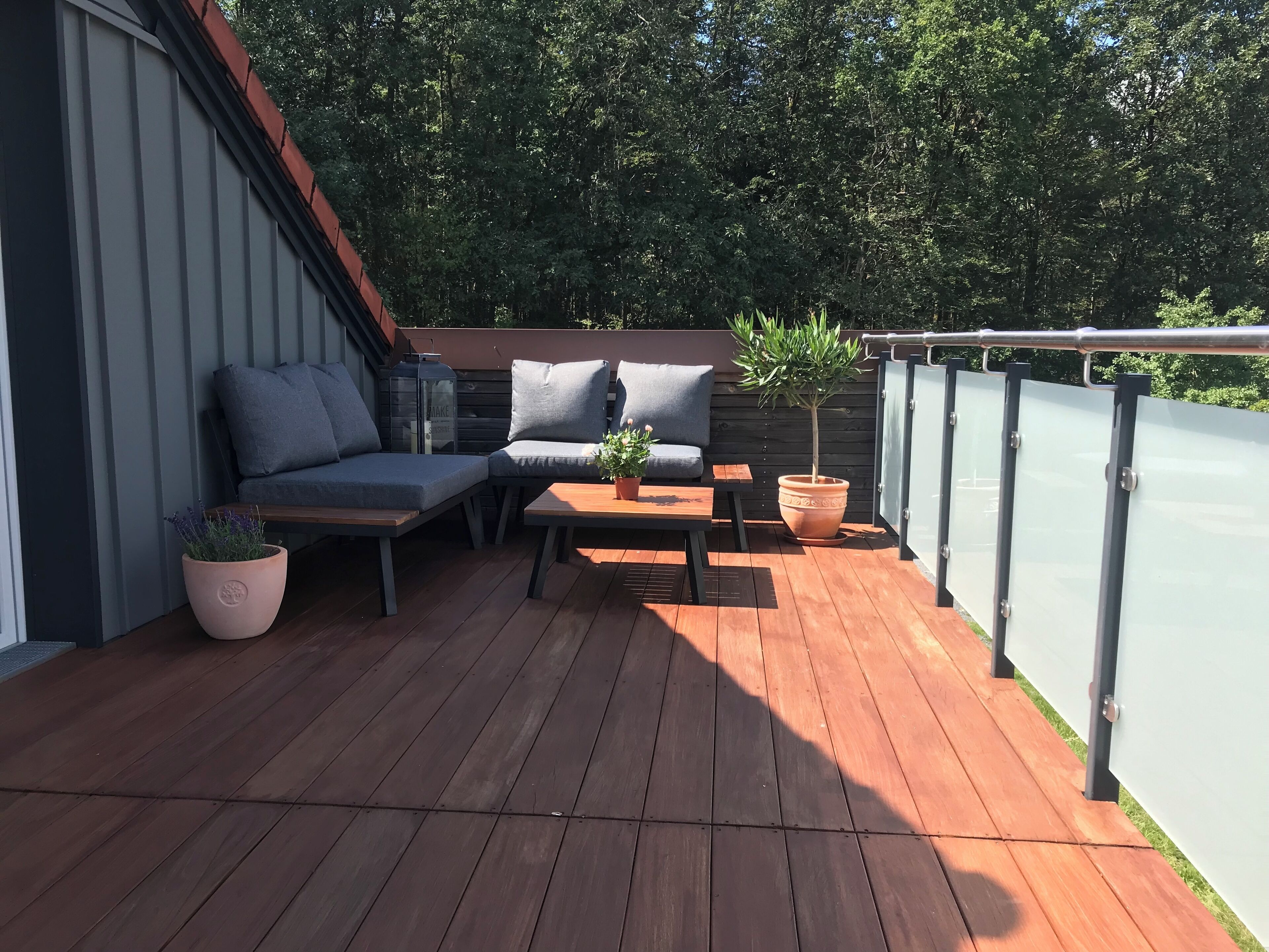 A wooden deck with a sofa, a table, and a potted plant.