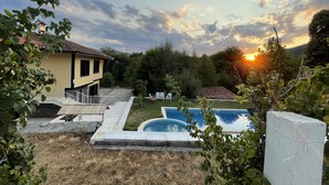 Una propiedad residencial con piscina, un patio cubierto y vistas al atardecer.