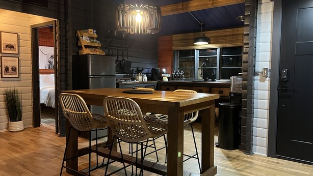 Cozinha moderna com mesa e cadeiras de madeira, geladeira e luminária pendente.