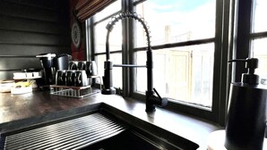 Uma cozinha moderna com uma pia de aço inoxidável, uma janela com vista para a cidade e uma bancada de madeira.