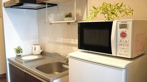 A compact kitchen with a microwave, sink, and a small plant on the counter. - JC HOTEL NAHA (Naha)