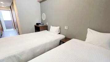 A hotel room with two single beds, a small wooden nightstand, a round mirror, and a door leading to a hallway.