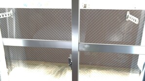 A metal gate with a mesh design, a metal handle, and a lock mechanism. - JC HOTEL NAHA (Naha)