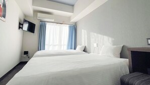 A hotel room with two beds, a flat-screen TV mounted on the wall, and a window with blue curtains. - JC HOTEL NAHA (Naha)