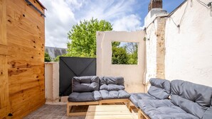 Une terrasse en bois avec un canapé et une table, un mur blanc et une porte en bois.