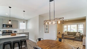 Una cocina moderna con una isla central, taburetes de bar e iluminación colgante.