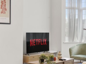 Relax in a clean and contemporary space with a flat-screen TV, comfortable seating, and a stylish cabinet.