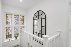 Stunning staircase with a black archway and stained glass windows.