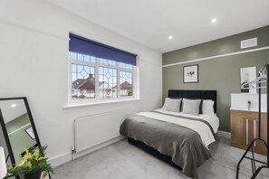Relax in a serene space with a large bed, green accent wall, and a view of the outside.