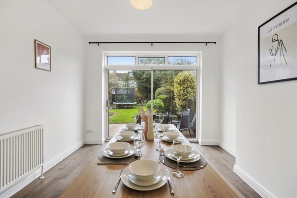 Enjoy meals with a view of the garden from this dining area, featuring a long table set for six.