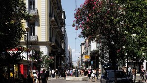 A street with buildings, a roundabout, and pedestrians. - Nur Aparthotel Athens (Athens)