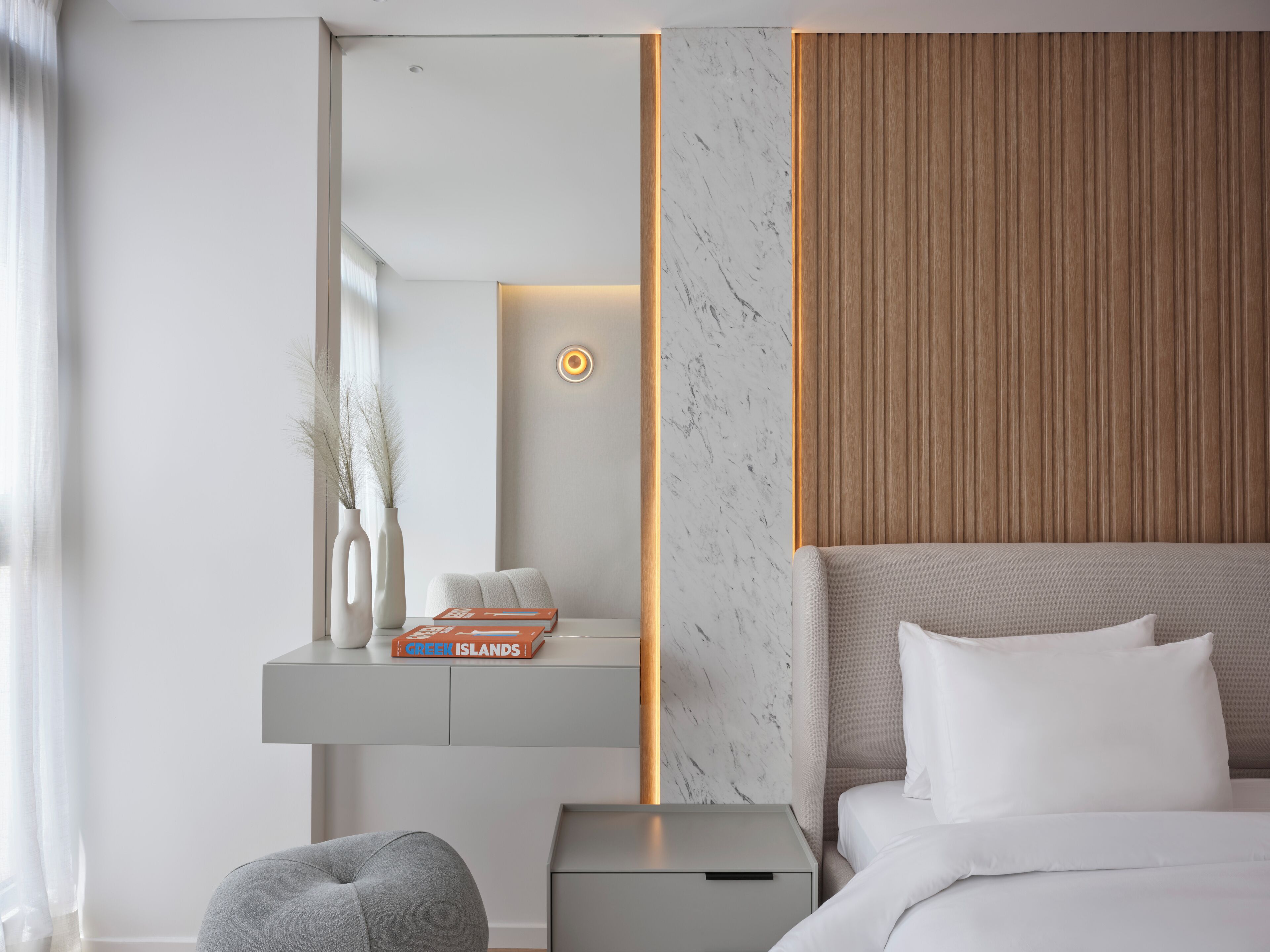 Una habitación de hotel moderna con cama, mesita de noche y velador.