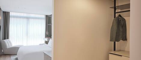 Une chambre d’hôtel moderne équipée d’un lit, d’une table de chevet et d’une armoire avec un porte-manteau.