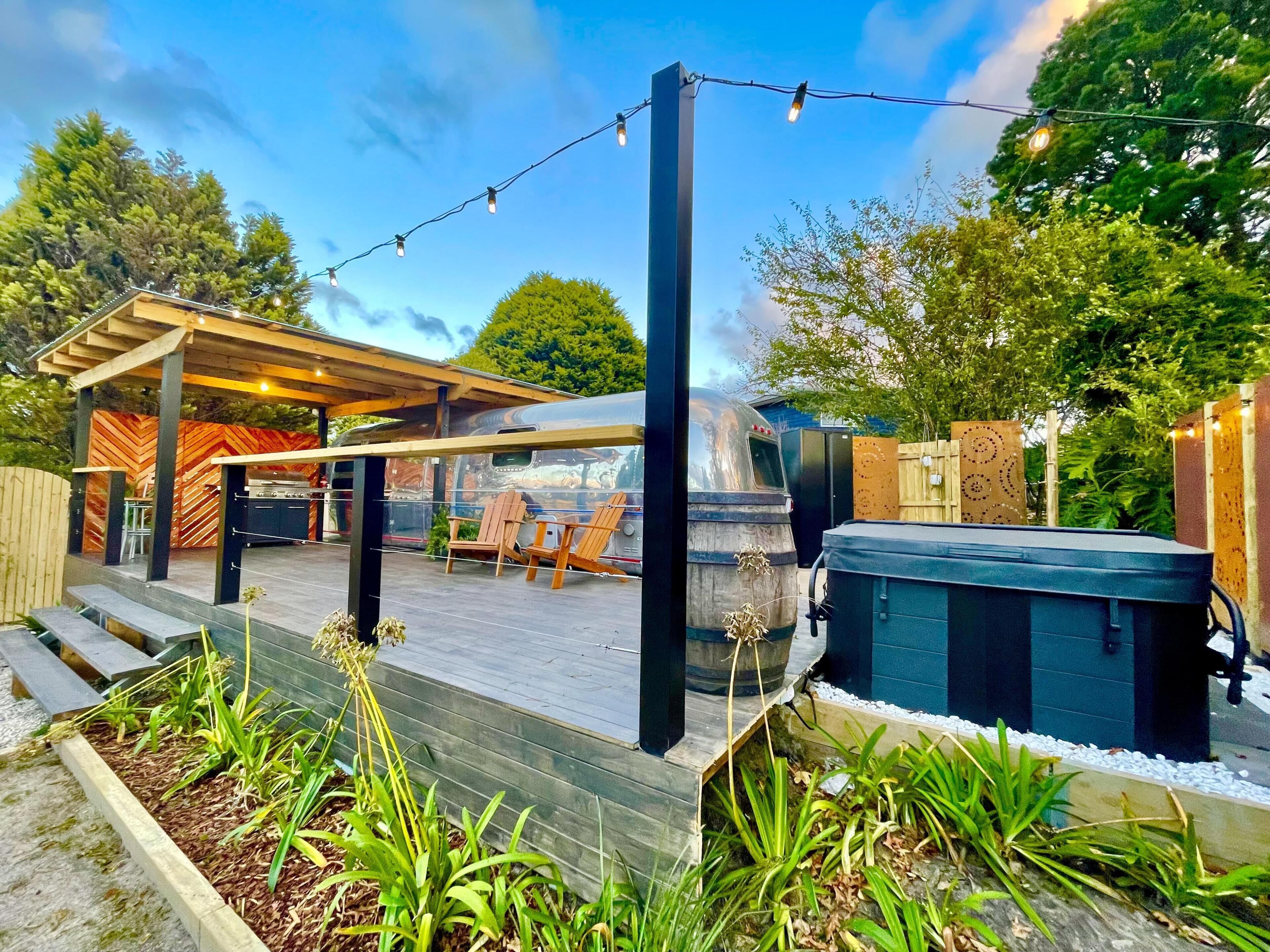 Eine überdachte Terrasse im Freien mit Grill, Sitzgelegenheit und Whirlpool.