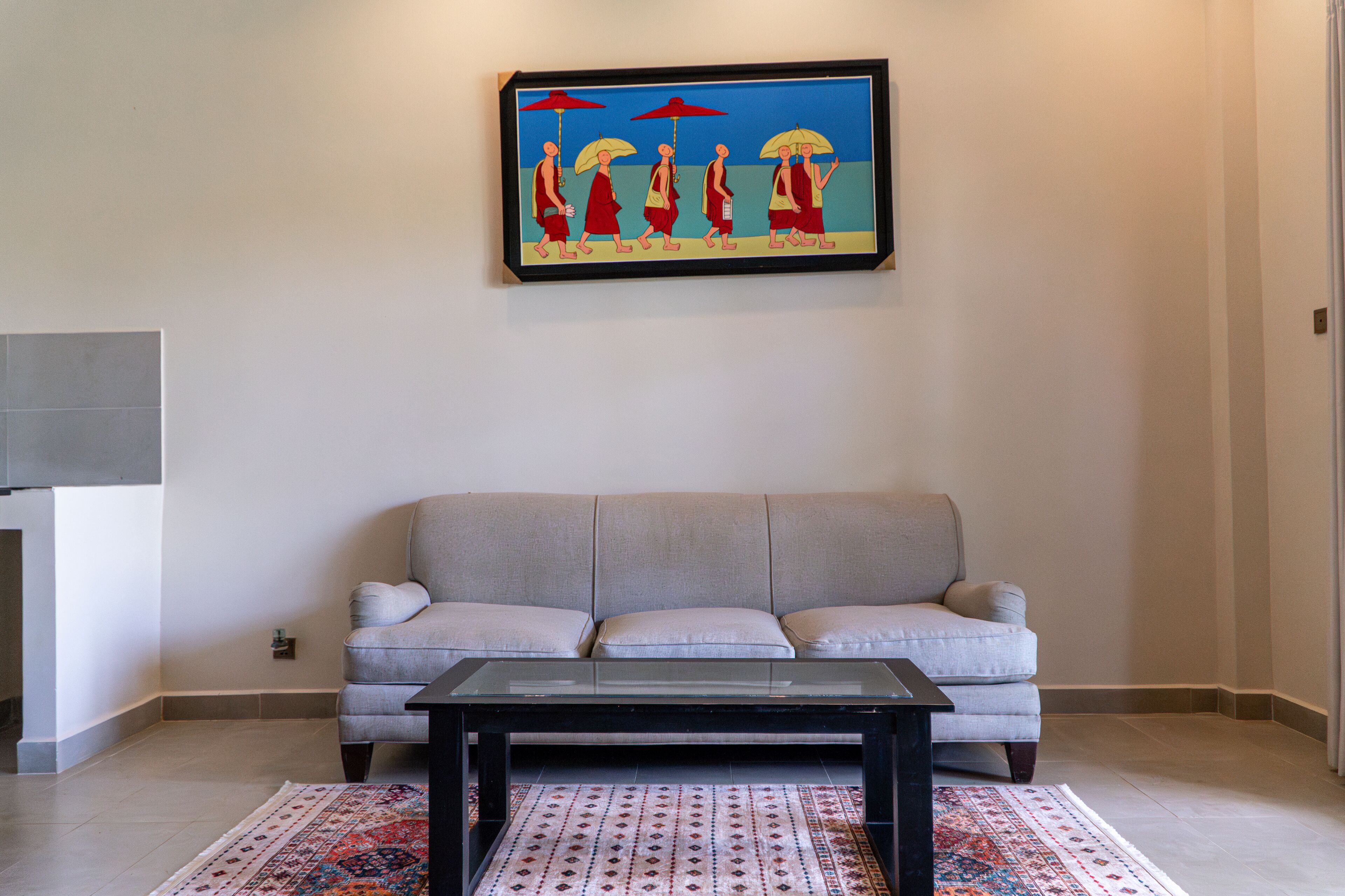 A living room with a sofa, a coffee table, and a framed artwork on the wall.