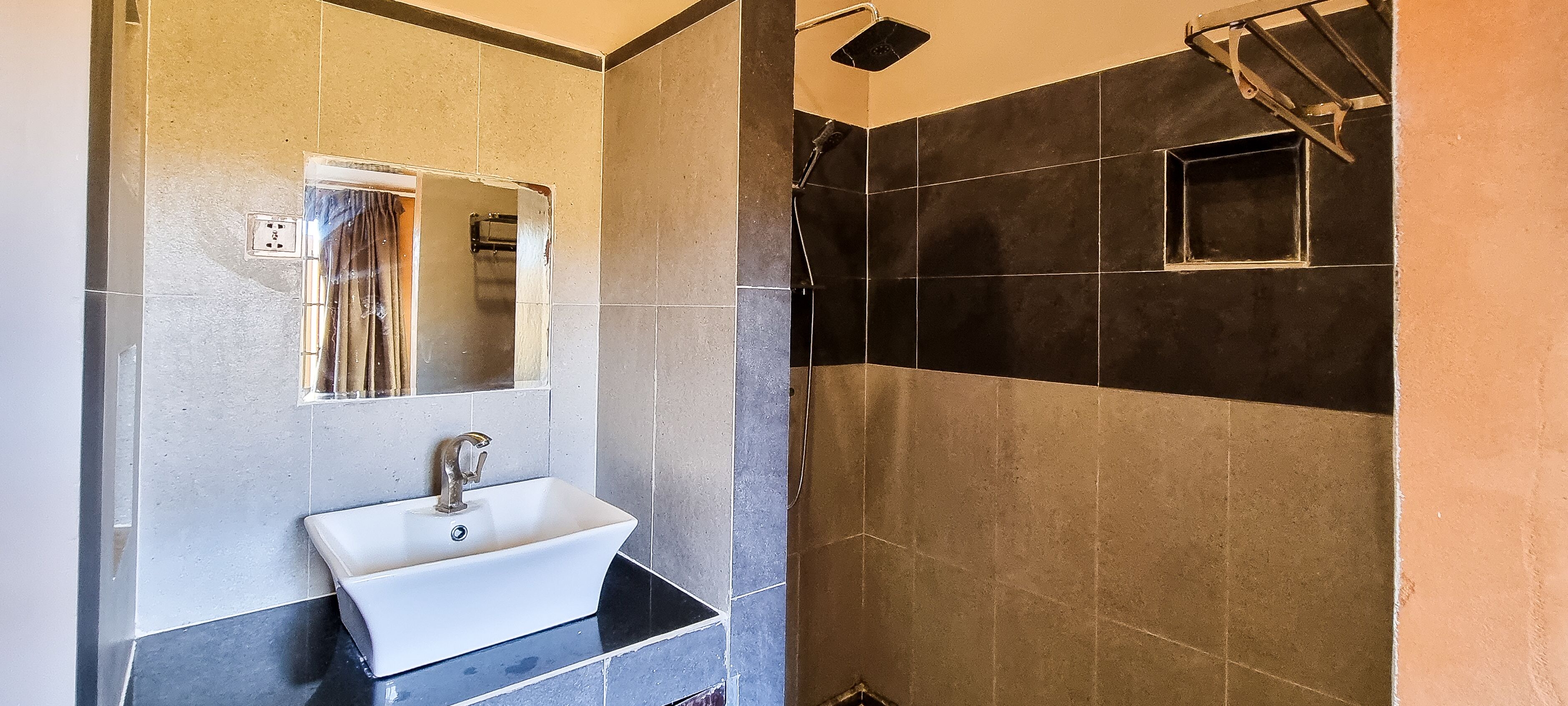 Baño con lavamanos, espejo y zona de ducha.