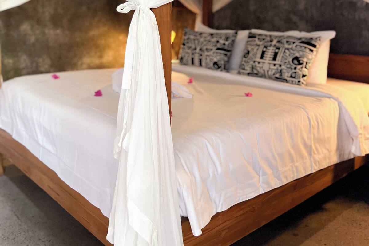A bed with a canopy, a pillow with a black and white pattern, and a wooden headboard.
