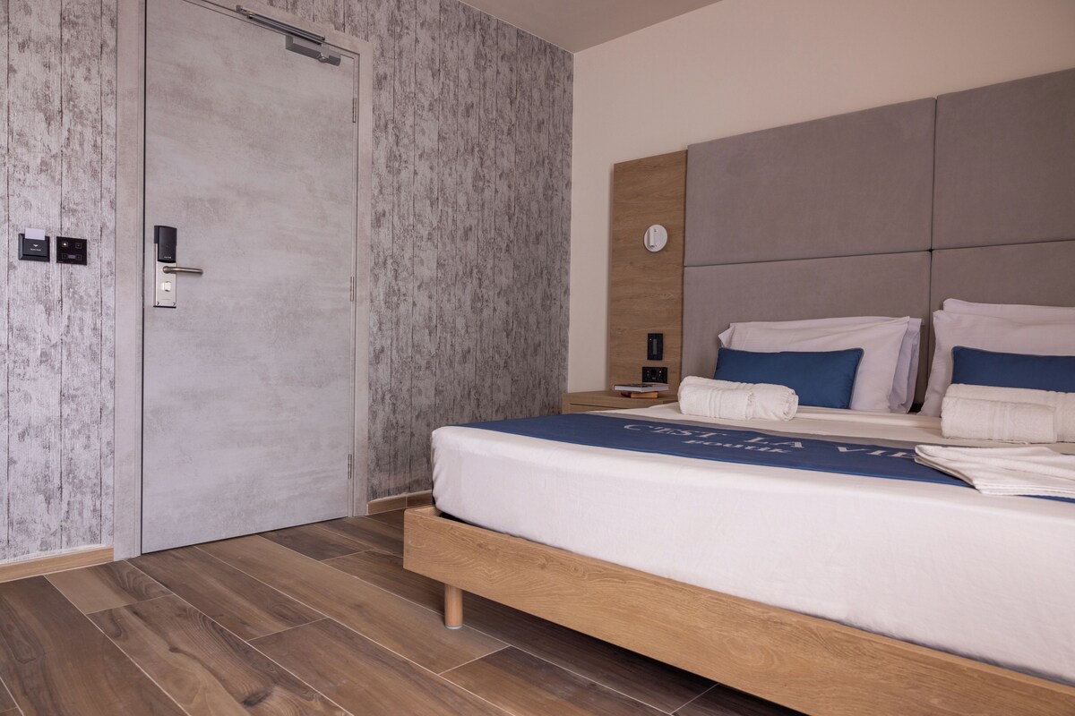 Un dormitorio moderno con una cama de madera, paredes grises con textura y suelo de madera.