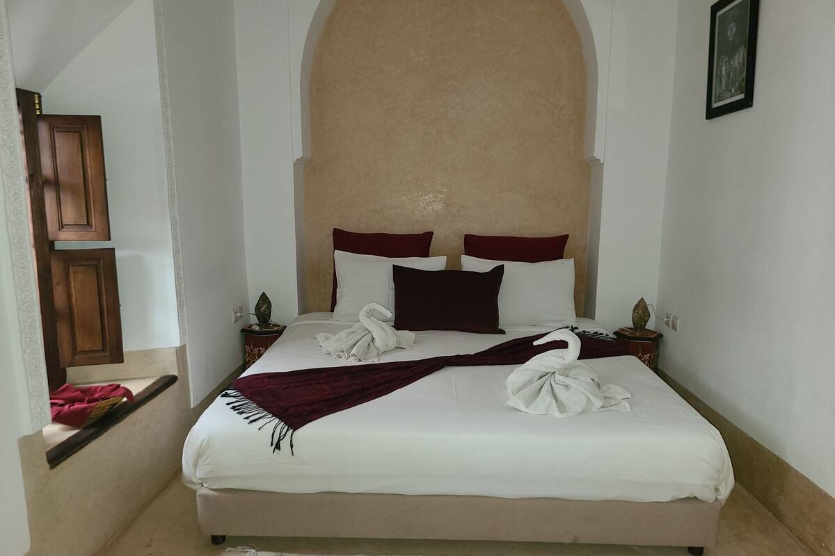 A neatly made bed with a headboard, pillows, and a blanket.
