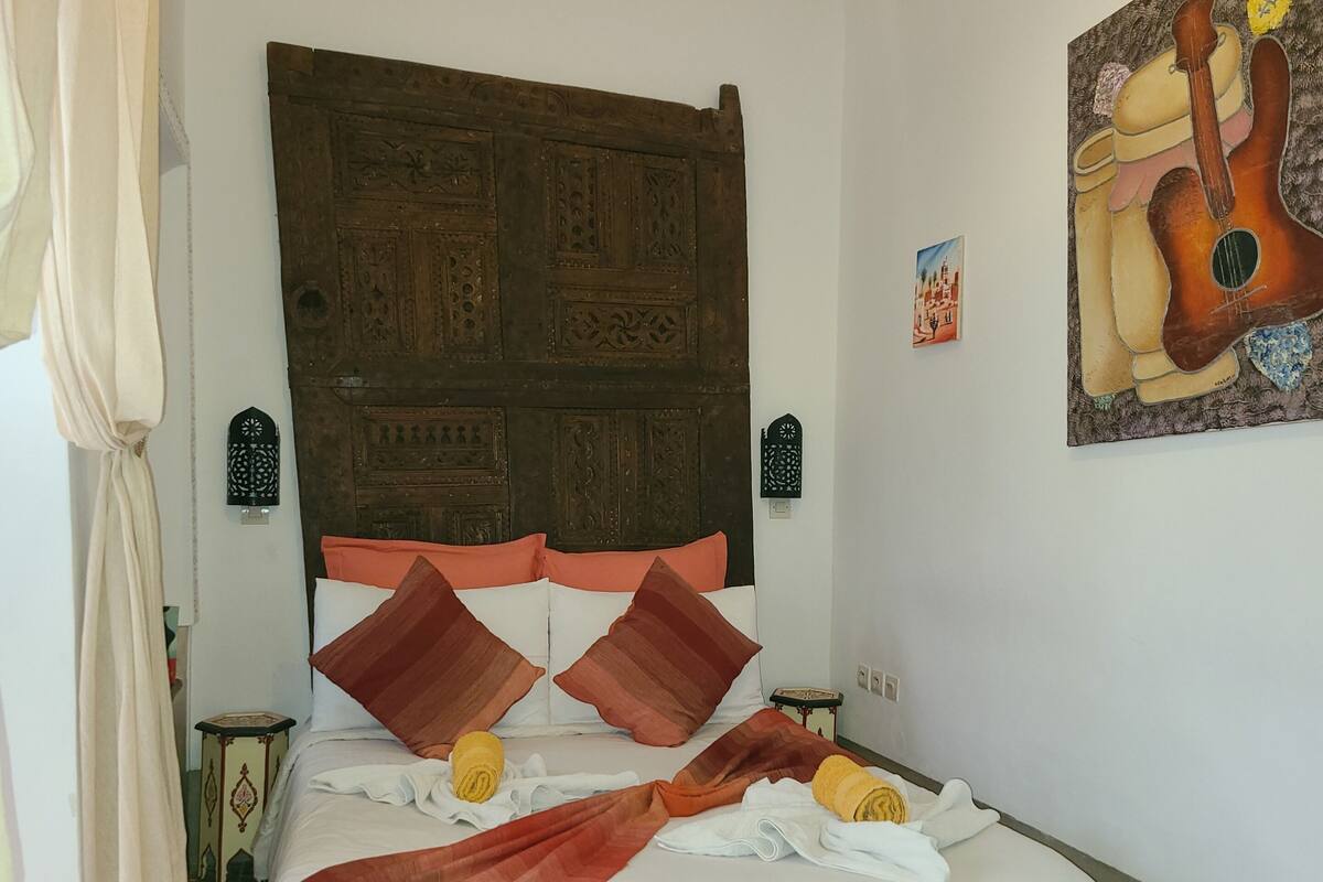 A bed with a wooden headboard, white bedding, and two wall-mounted lamps.