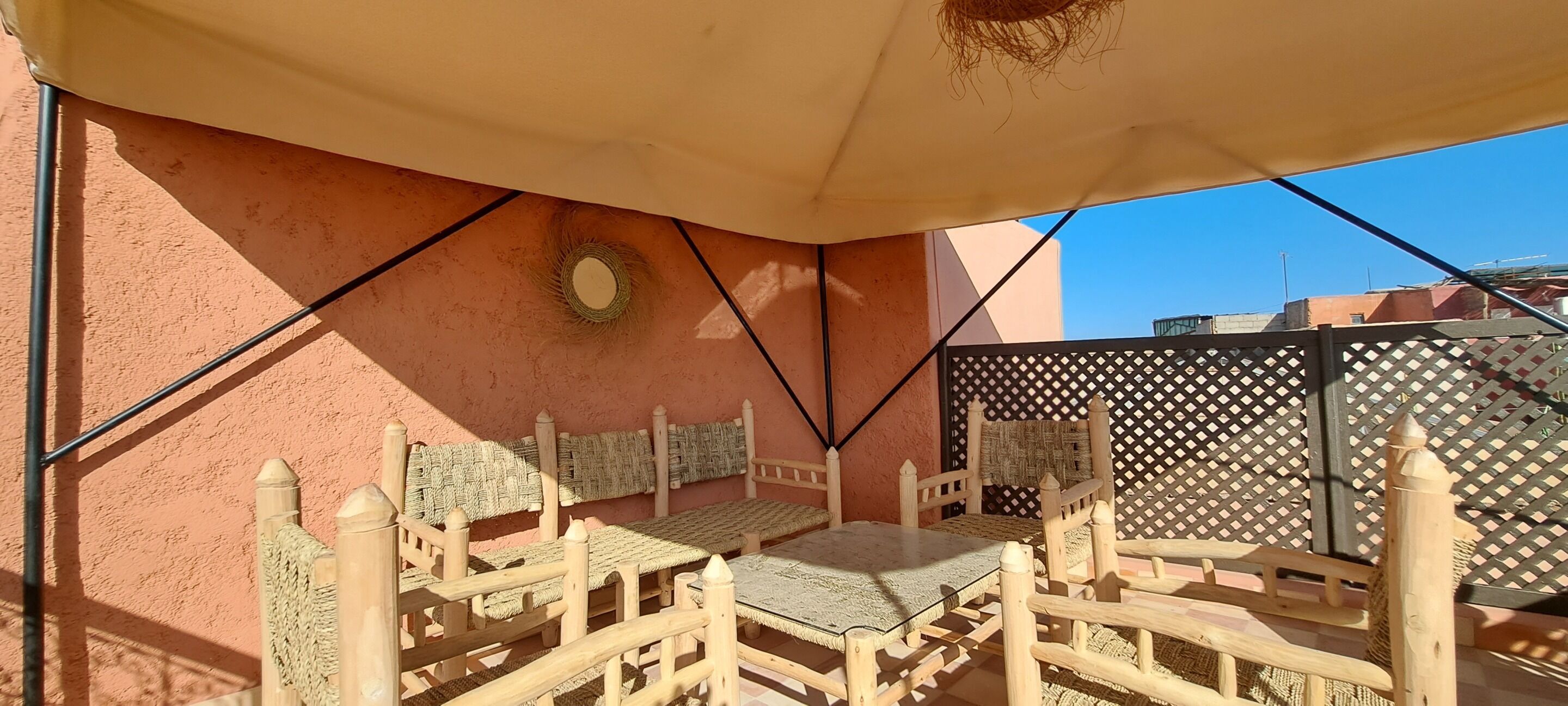 A covered outdoor seating area with wooden furniture and a lattice fence.