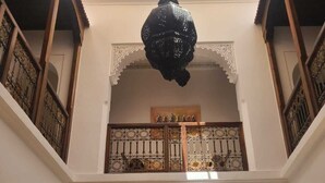 A multi-level interior with ornate railings, a central chandelier, and a decorative archway. - Riad parfum d'orient (Marrakech)