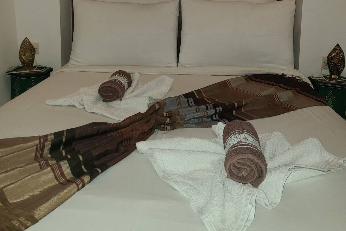 A neatly made bed with a headboard, pillows, and towels.