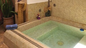 A spa area with a large bathtub, decorative wall tiles, and a hanging lantern. - Riad parfum d'orient (Marrakech)