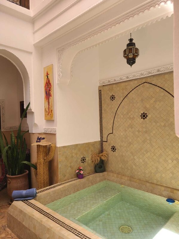 Un área de spa con una bañera grande, azulejos decorativos y un farol colgante.