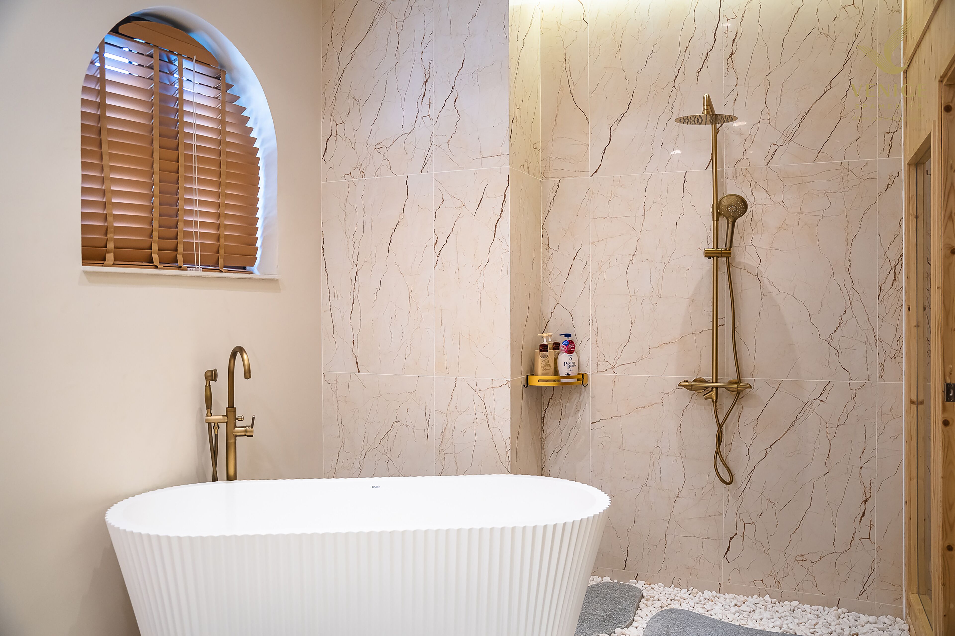 A bathroom with a freestanding bathtub, a shower with a handheld showerhead, and a window with blinds.