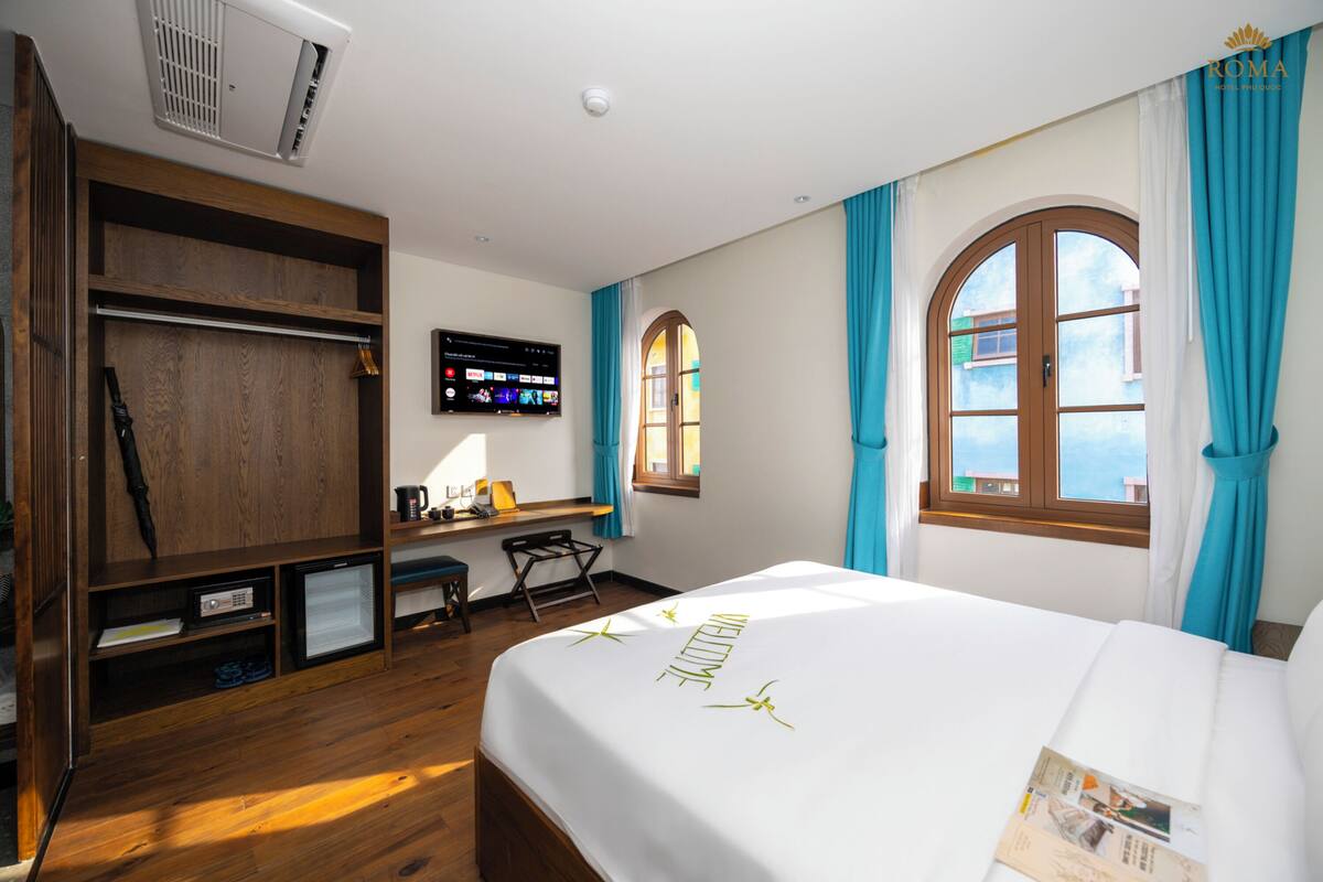 Una habitación de hotel con cama, escritorio, televisor y armario.