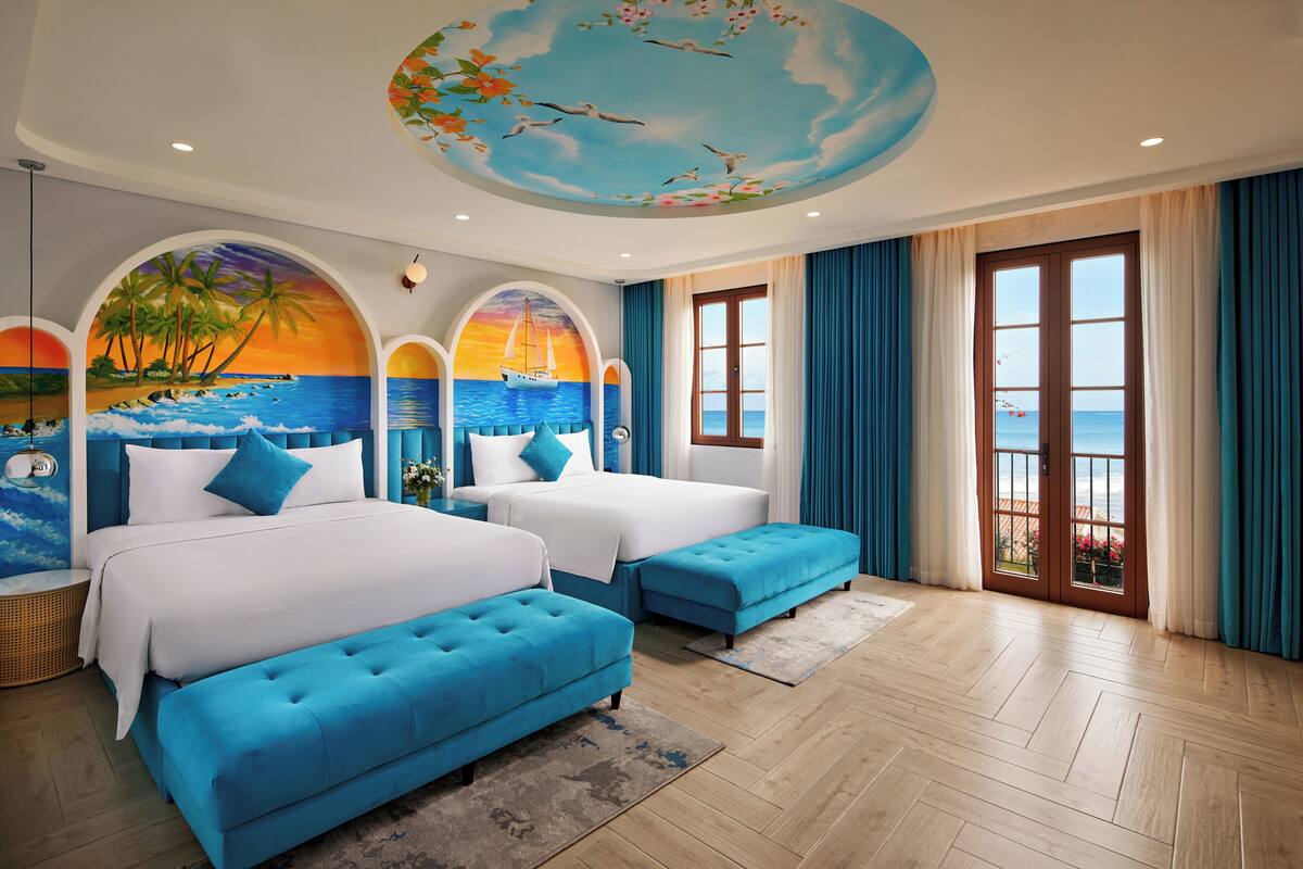 Habitación de hotel con dos camas, vista al mar y un mural en el techo.
