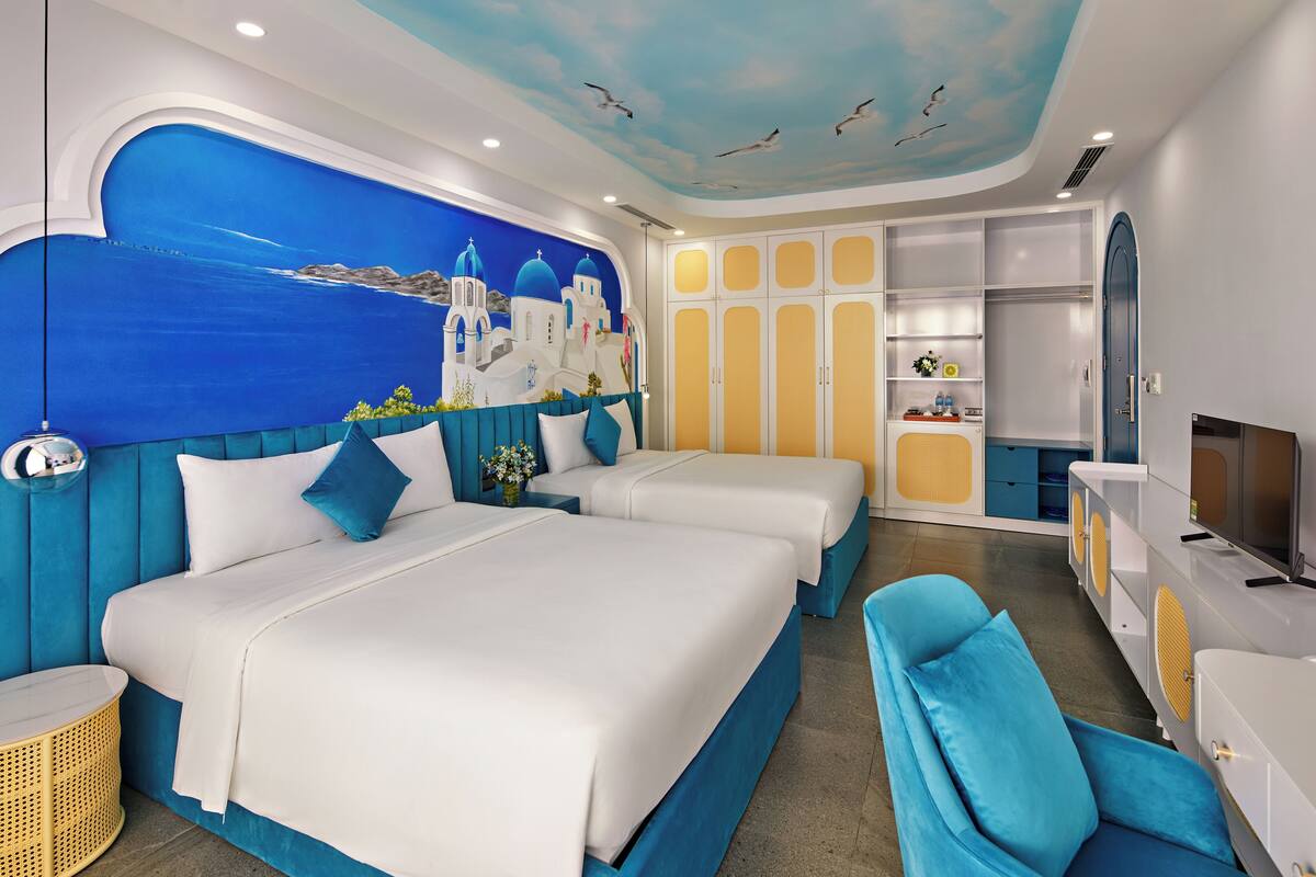 Habitación de hotel con dos camas, un televisor, un armario y un mural en el techo.