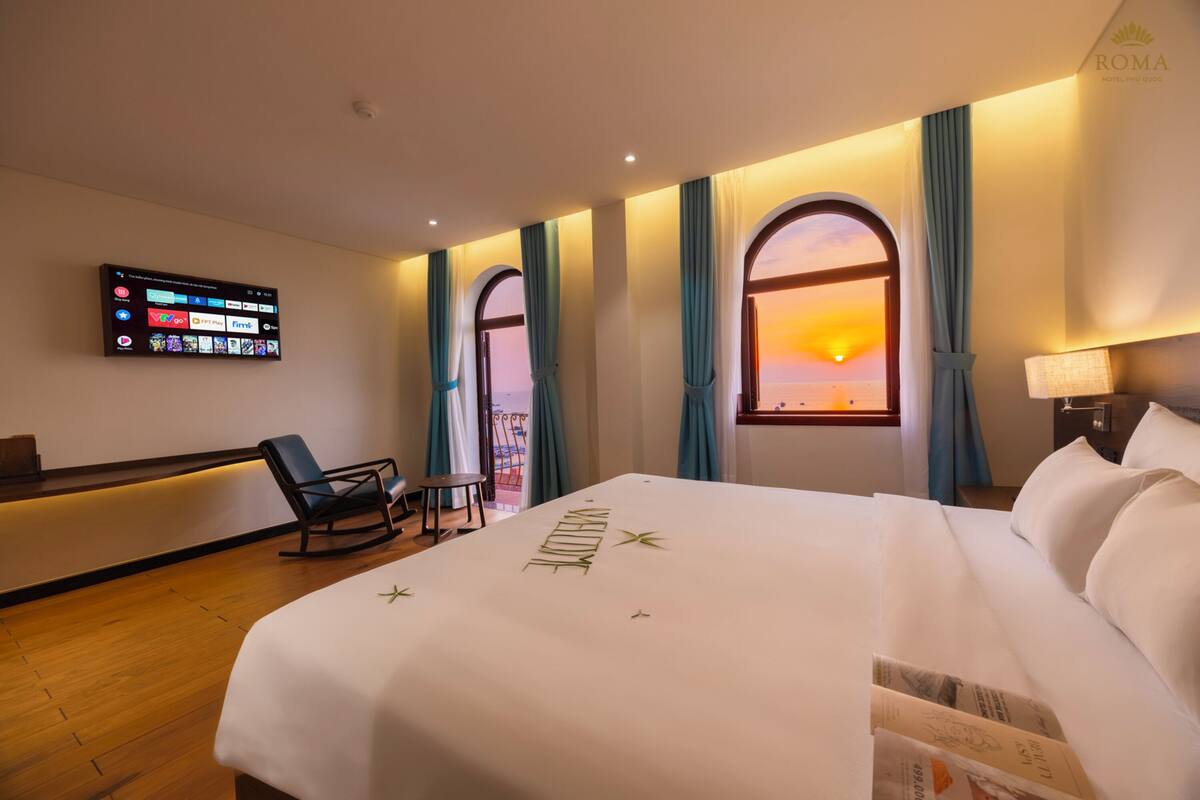 Habitación de hotel con cama, televisor montado en la pared, escritorio y silla.