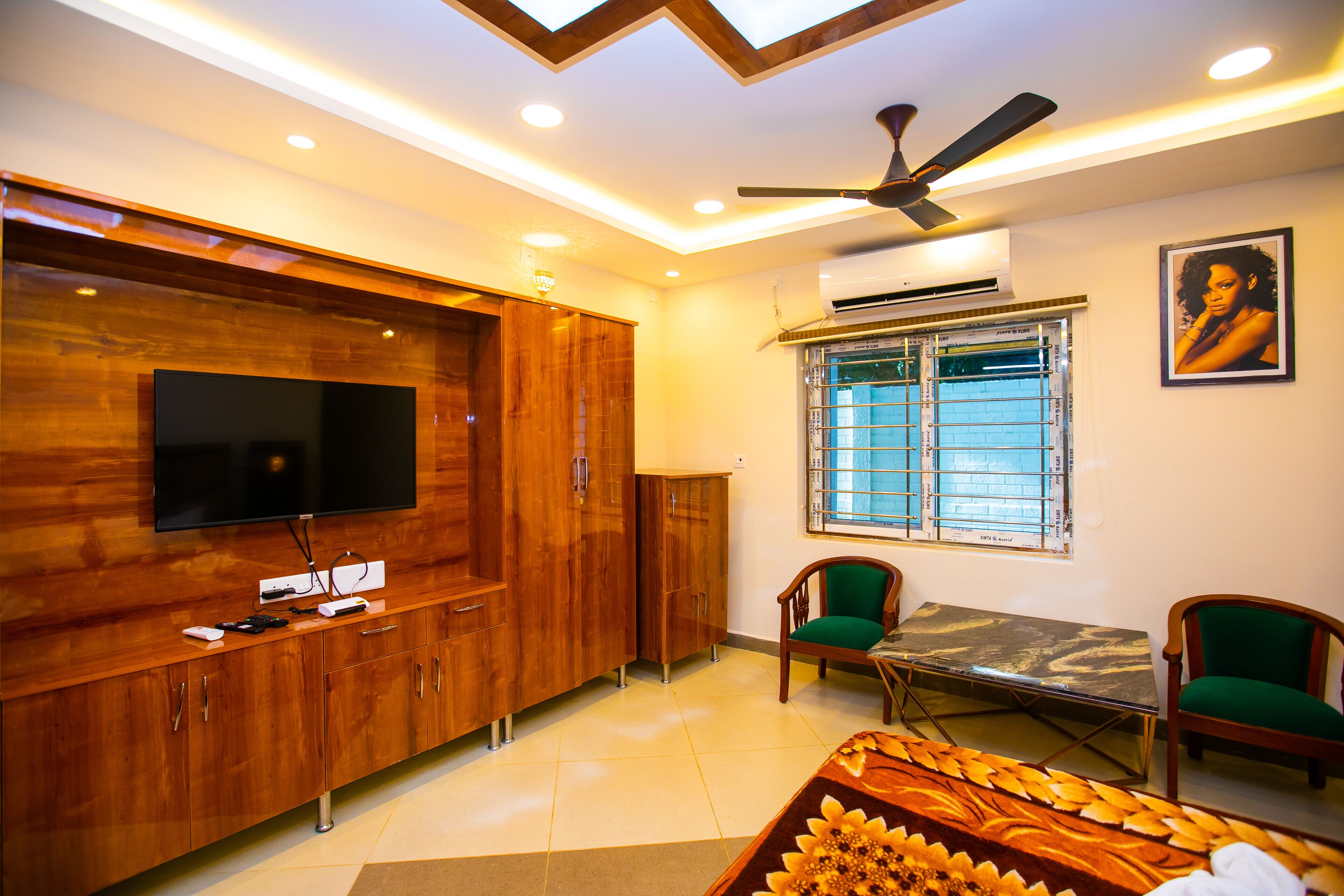 Una sala moderna con televisión de pantalla plana, muebles de madera, ventilador de techo y una mesa de comedor con sillas.