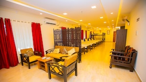A hotel lobby with a long reception desk, several sofas, and chairs arranged for guests. - Queens Paradise Estate (Vanur)