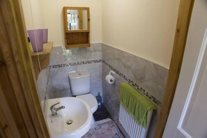 A compact bathroom with a sink, toilet, and a mirror above the sink.
