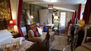 A cozy room with a bed, a sofa, and a dining area. - a Quirky Garden Building in an Orchard (Ryton)