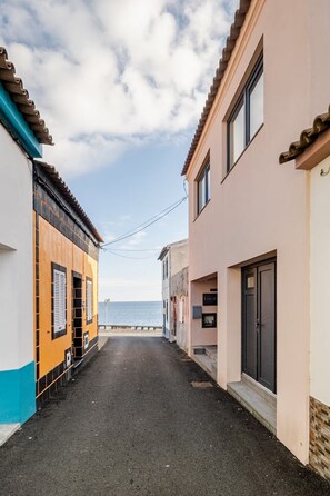 A narrow street with buildings on either side, a clear sky, and a view of the sea in the distance. - Spacious Seaside apartment A - Faraway (Lagoa)