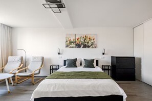 A modern hotel room with a large bed, two bedside tables, a chair, a desk, and a wardrobe. - Spacious Seaside apartment A - Faraway (Lagoa)