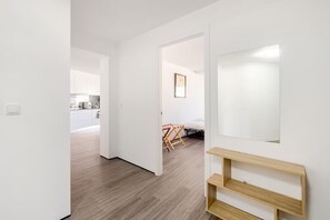 A modern interior with a wooden floor, white walls, a kitchen area, and a bed with a wooden headboard. - Spacious Seaside apartment A - Faraway (Lagoa)
