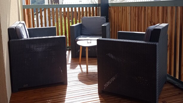Une terrasse en bois, meublée de meubles en osier, avec vue sur un paysage montagneux.