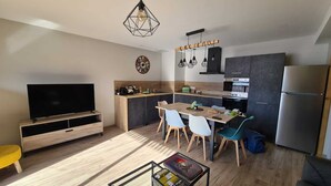 Une cuisine moderne avec un coin repas, un téléviseur et un réfrigérateur.