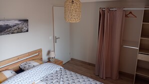 Une chambre à coucher comprenant un lit, une table de chevet, un luminaire suspendu, une armoire et une porte.