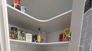 A kitchen with white shelves, containing various kitchen items like cups, plates, and cooking oil. - Gladstone Super Home Fully Fenced With Central Aircondioning (New Auckland)