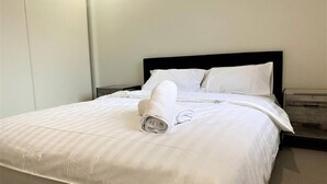 A neatly made bed with white linens and a rolled towel on the bed. - Gladstone Super Home Fully Fenced With Central Aircondioning (New Auckland)