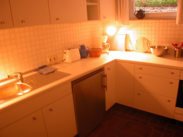 A kitchen with white cabinets, a sink, and a window with a view of greenery outside.