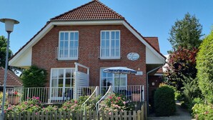 A two-story brick building with a tiled roof, a sign indicating it is a restaurant, and a small outdoor seating area with a table and chairs.