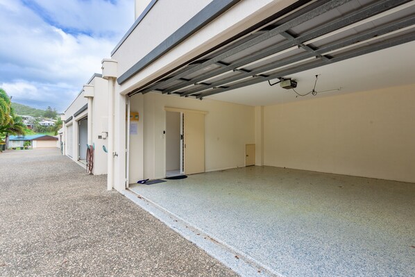 A building with a garage door, a door, and a small room with a ceiling fan.