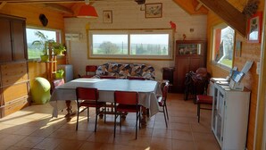 Uma área de refeições com uma mesa grande, cadeiras e uma janela com vista para o exterior.